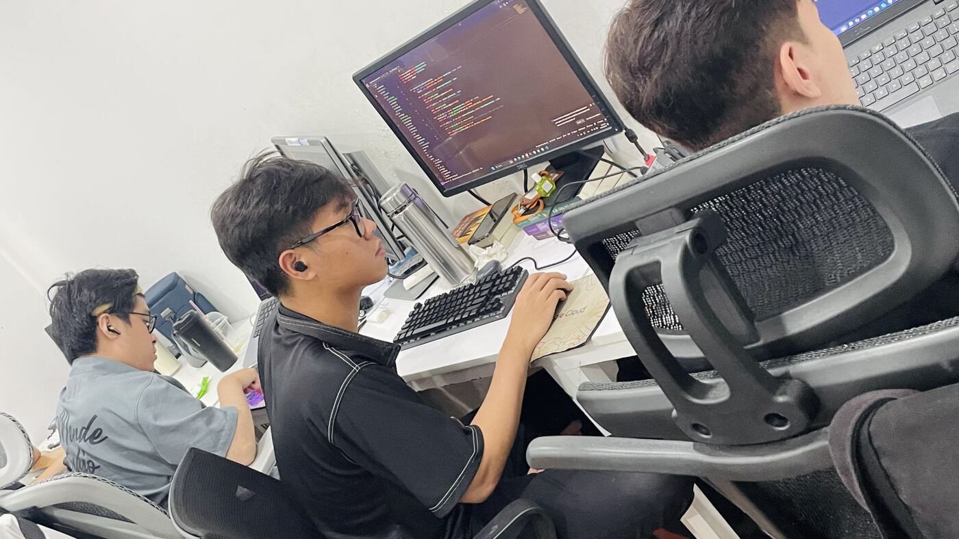 Lập trình viên MONA viết code trên màn hình lớn tại chỗ ngồi văn phòng